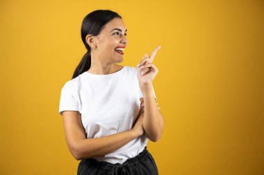 Genç ve güzel bir kadın sağ taraftaki boşluğa bakıp gülümsüyor. Sarı arka planda günlük beyaz tişört ve kırmızı ruj.