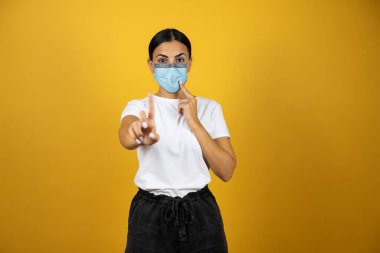 Koronavirüs maskesi takan genç bir kadın maskeyi kullanmanın zorunlu olduğu uyarısını yapıyor. covid-19