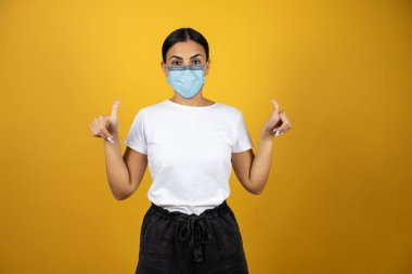 Koronavirüs takan genç bir kadın yüzünü maskeliyor ve salgını durdurmak için kullanılması gerektiğini onaylıyor. Covid 19