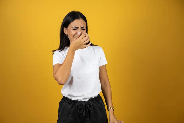 Jovem Mulher Bonita Sobre Fundo Amarelo Isolado Cheirando Algo Fedorento — Fotografia de Stock