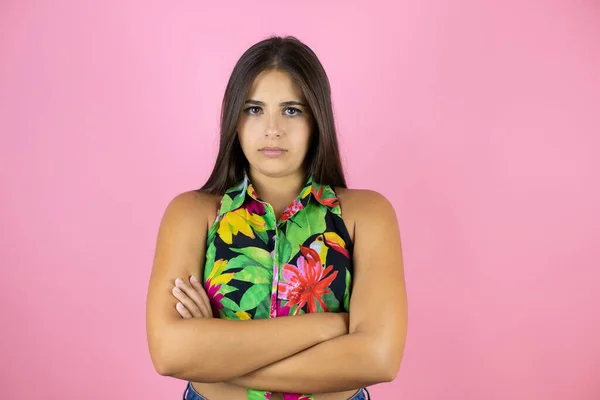 Young beautiful woman over pink background skeptic and nervous, disapproving expression on face with crossed arms