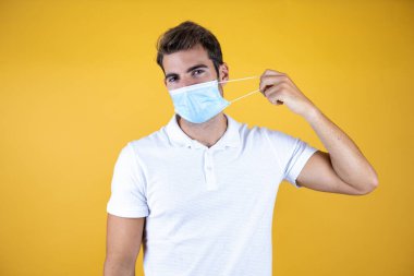 Tecrit edilmiş geçmişinde tıbbi maske takan yakışıklı bir adam. Çıkarmaya çalışıyorum. Sağlık hizmetleri kavramı.