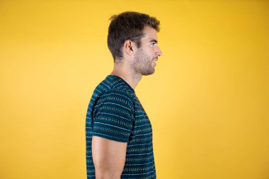 Sarı arka planda duran yakışıklı genç adam doğru gülümsemeye bakıyor.