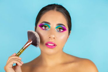 Canlı makyajlı ve mavi arka planda fırçası olan kadın modelin güzel portresi.