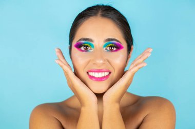 Mavi arka planda canlı makyajla gülümseyen kadın modelin güzel portresi.