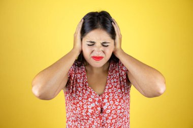 İzole edilmiş sarı arka plan üzerinde genç ve güzel bir kadın. Yüksek sesli müzik sesi için elleri ve rahatsız edici ifadeleri olan kulakları var. Sağır kavramı.
