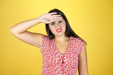 Sarı arka plan üzerinde genç ve güzel bir kadın. Hastalık, ateş, grip ve virüs için alnına dokunuyor.