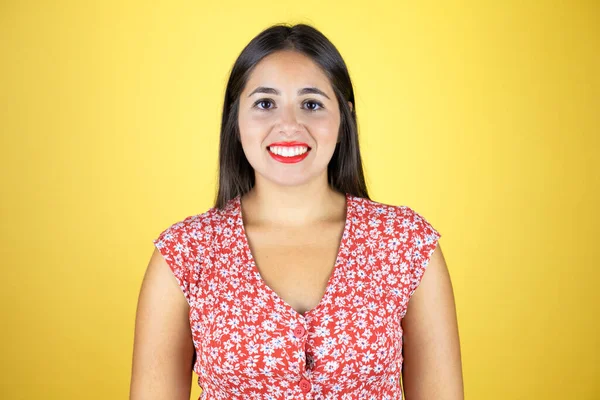 Genç ve güzel bir kadın, izole edilmiş sarı arka planda gülümsüyor ve kameraya bakıyor.