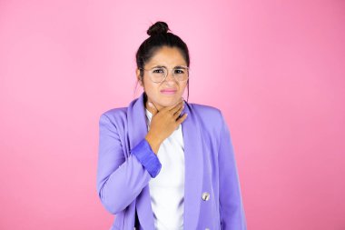 Genç ve güzel bir iş kadını pembe arka planda acı çeken bir boyuna dokunuyor, grip, mantar ve enfeksiyon yüzünden boğaz ağrısı çekiyor.