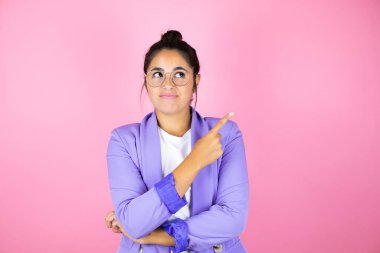 Soyutlanmış pembe arka planda genç ve güzel bir iş kadını mutlu bir şekilde gülümsüyor.