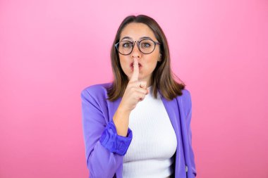 Soyutlanmış pembe arka planda genç ve güzel bir iş kadını sessiz olmak istiyor. Sessizlik ve gizli konsept.