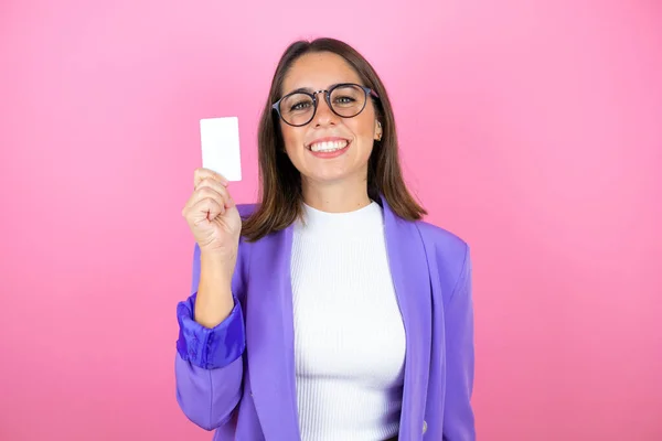 Young beautiful business woman over isolated pink background smiling and showing white card
