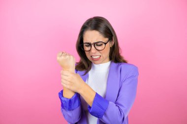 Genç ve güzel bir iş kadını pembe arka planda acı çekiyor ellerde ve parmaklarda ağrı, eklem iltihabı.