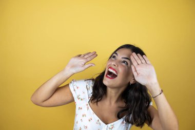 Sarı arka planda güzel bir kadın kolları yukardan düşen bir şey gibi havada korkmuş.