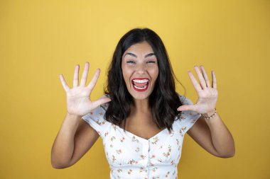 Mutlu ve kendinden emin bir şekilde gülümserken on numarayı göstererek.