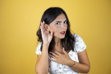 Sarı arka planda güzel bir kadın kulak misafiri oldu. Dedikoduları ve dedikoduları dinliyor.