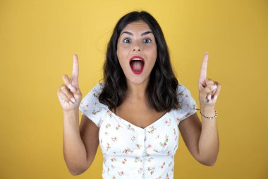 Sarı arka planda güzel bir kadın kameraya bakıp parmaklarını kaldırıp kollarını kaldırdığında şaşırmış ve şaşırmıştı.