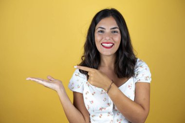 Sarı arka plandaki güzel kadın şaşırdı ve elindeki bir şeyi gösterip işaret etti..