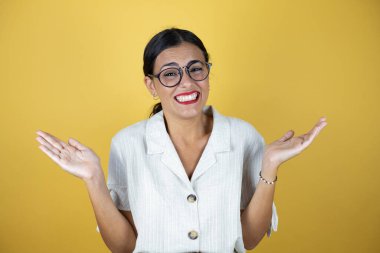 Sarı arka planda güzel bir kadın çılgın ve kızgın bağırıyor ve bağırıyor agresif bir ifade ve kollarla..