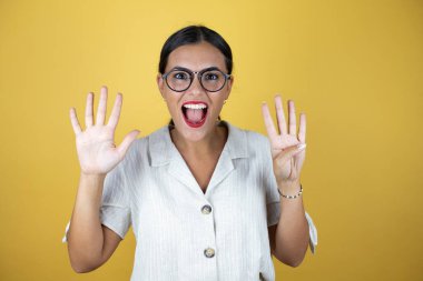 Sarı arka planda güzel bir kadın dokuz numarayı gösterip işaret ederken kendinden emin ve mutlu bir şekilde gülümsüyor..