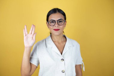 Sarı arka planda güzel bir kadın garip bir jest yapıyor..