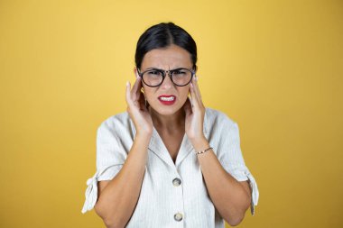 Sarı arka planda güzel bir kadın. Başı ağrıdığı için elleri başının üstünde. Stres yüzünden. Migren ağrısı..