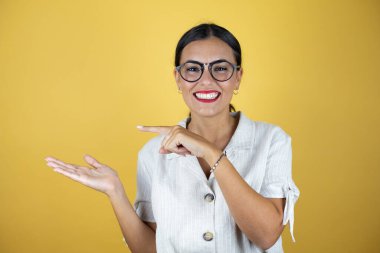 Sarı arka plandaki güzel kadın şaşırdı ve elindeki bir şeyi gösterip işaret etti.