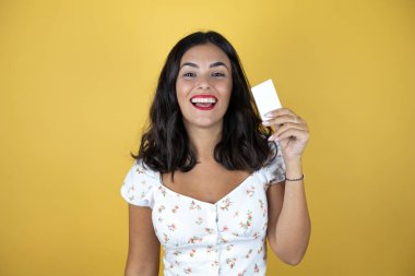 Sarı arka planda güzel bir kadın gülümsüyor ve elinde beyaz kart tutuyor.