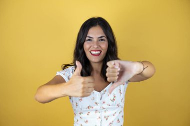 Sarı arka planda güzel bir kadın baş parmaklarını yukarı aşağı hareket ettiriyor, anlaşmazlık ve anlaşma ifadesi. Çılgın çatışma