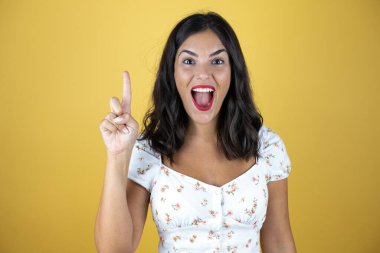 Sarı arka planda güzel bir kadın şaşırmış, yukarı bakıyor..