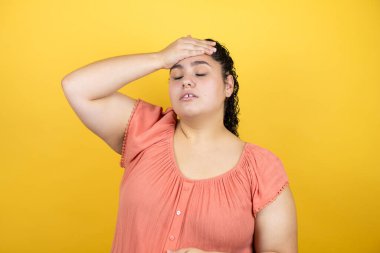 Sarı arka planda kıvırcık saçlı genç bir kadın bir elini kafasına koyup sanki bir şey unutmuş gibi gülümsüyordu.