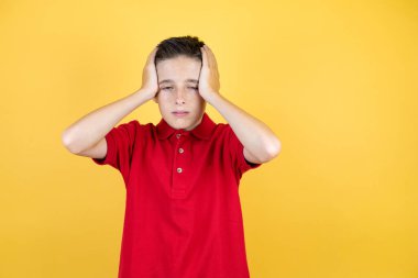 Genç, güzel bir çocuk, izole edilmiş sarı arka planda. Yorgun ve sıkılmış görünüyor.