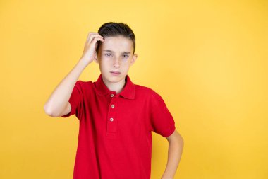 İzole edilmiş sarı arka planı olan genç ve güzel bir çocuk soru sormayı merak ediyor. Şüpheyle karışık, kafa kafaya düşünerek.