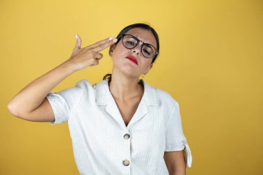 Sarı arka planda güzel bir kadın kendini vuruyor ve öldürüyor. Elini ve parmaklarını silah gibi kullanıyor. İntihar jesti..