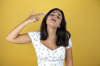 Sarı arka planda güzel bir kadın kendini vuruyor ve öldürüyor. Elini ve parmaklarını silah gibi kullanıyor. İntihar hareketi..