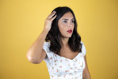 Sarı arka planda güzel bir kadın gülümsüyor ve parmakları kafasında bir fikri olduğunu düşünüyor..