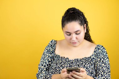 Sarıya boyanmış kıvırcık saçlı, genç ve güzel bir kadın telefonuyla mesajlaşıyor.