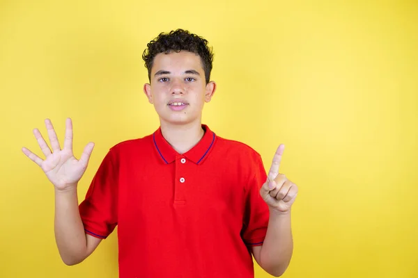 漂亮的少年男孩在孤零零的黄色背景上 带着自信而快乐的微笑 用手指指指着六号 — 图库照片