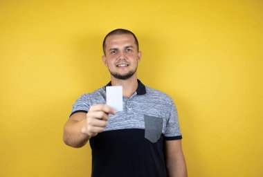 Rus adam izole edilmiş sarı arka planda beyaz bir kart gösteriyor..
