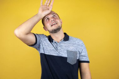 Rus adam solgun sarı arka planda duruyor. Hastalık, ateş, grip ve soğuk algınlığı için alnına dokunuyor.