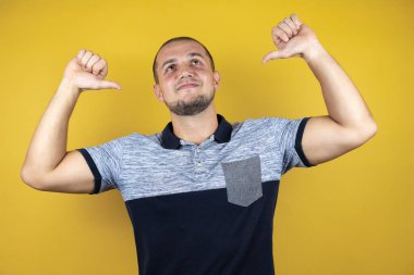 İzole edilmiş sarı arka planda duran Rus adam yüzünde gülümsemeyle kendinden emin görünüyor, kendini gururlu ve mutlu bir şekilde gösteriyor..