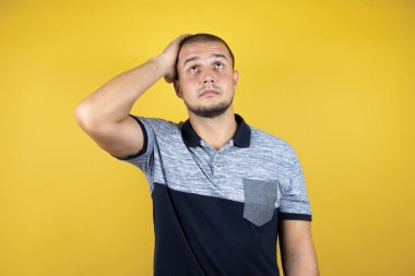 Sarı arka planda dikilen Rus adam, alnındaki bir sorun yüzünden endişeli ve stresli, gergin ve bunalımda.