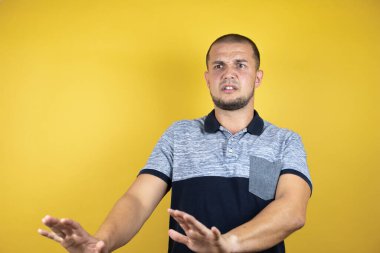Korkulu sarı arka planda dikilen Rus adam korku ifadesinden korkuyor ve dehşete düşüyor. El hareketlerini durdur, şok içinde bağır. Panik konsepti.