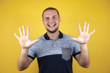 Mutlu ve kendinden emin bir şekilde gülümserken on numarayı göstererek..