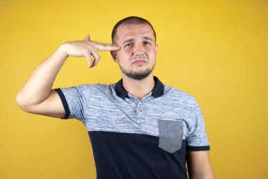 Rus adam sarı arka planda dikiliyor. Kendini vuruyor ve öldürüyor. Silah gibi el ve parmakları işaret ediyor..