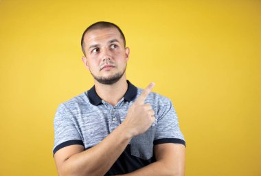 İzole edilmiş sarı arka planda dikilen Rus adam parmağını yana doğru gösteriyor..