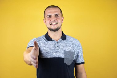 Sarı arka planda dikilen Rus adam dostça bir selamlama ve hoş geldin hediyesi olarak el sıkışır.