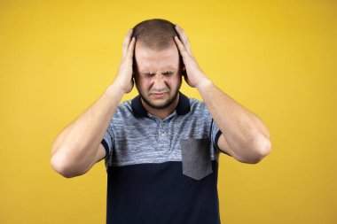 Başı ağrıdığı ve başı ağrıdığı için baş ağrısı ve stresten kıvranan sararmış sarı arka planda duran Rus bir adam.