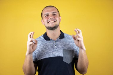 Rus adam sarı arka planda duruyor. Umut dolu bir gülümsemeyle işaret ediyor.