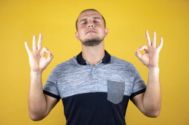 Rus adam sararmış arka planda duruyor rahatla ve gülümse gözleri kapalı parmaklarıyla meditasyon hareketi yapıyor. Yoga konsepti.